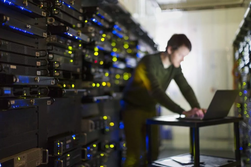 Man standing in server room, looking at computer