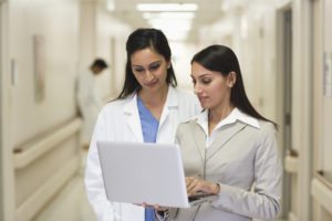 Businesswoman showing laptop to doctor in hospital