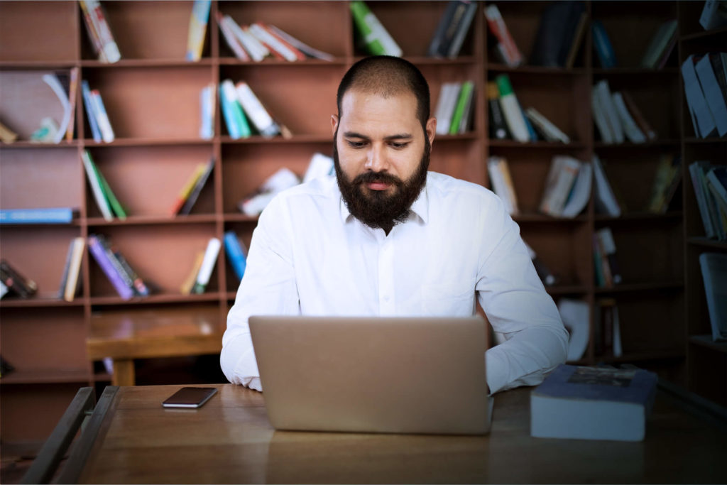 Man at university works on laptop, utilizing education unified communications services