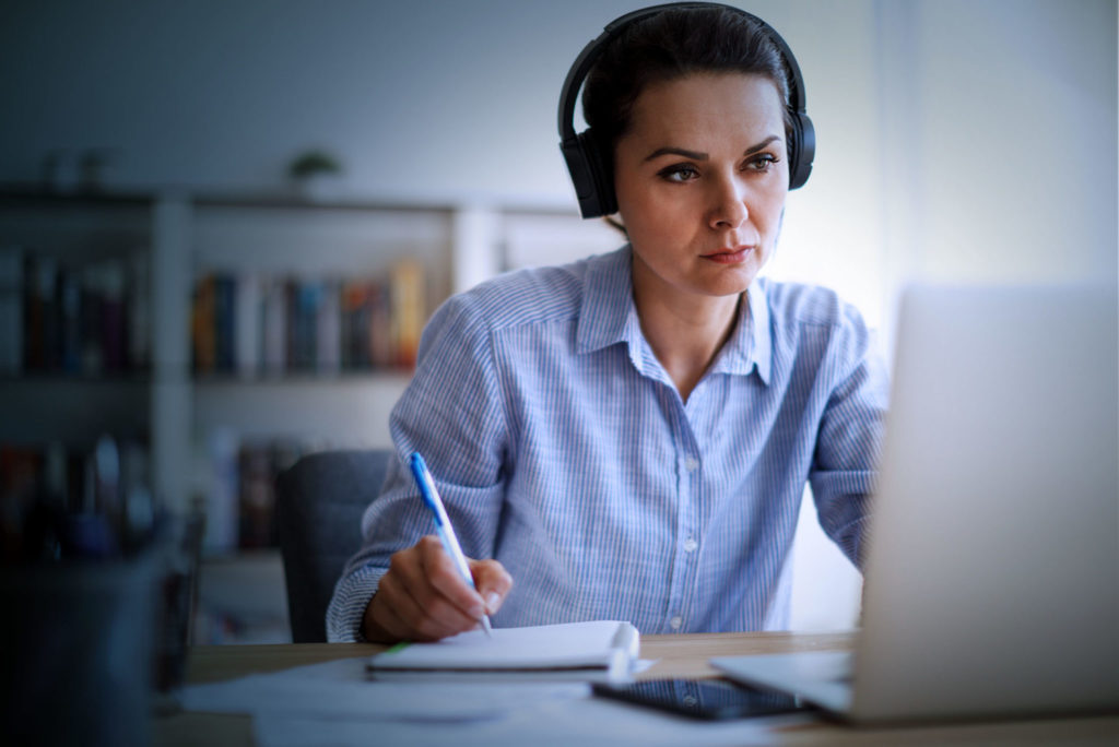 woman looking at laptop with notebook and pen. benefits of microsoft teams