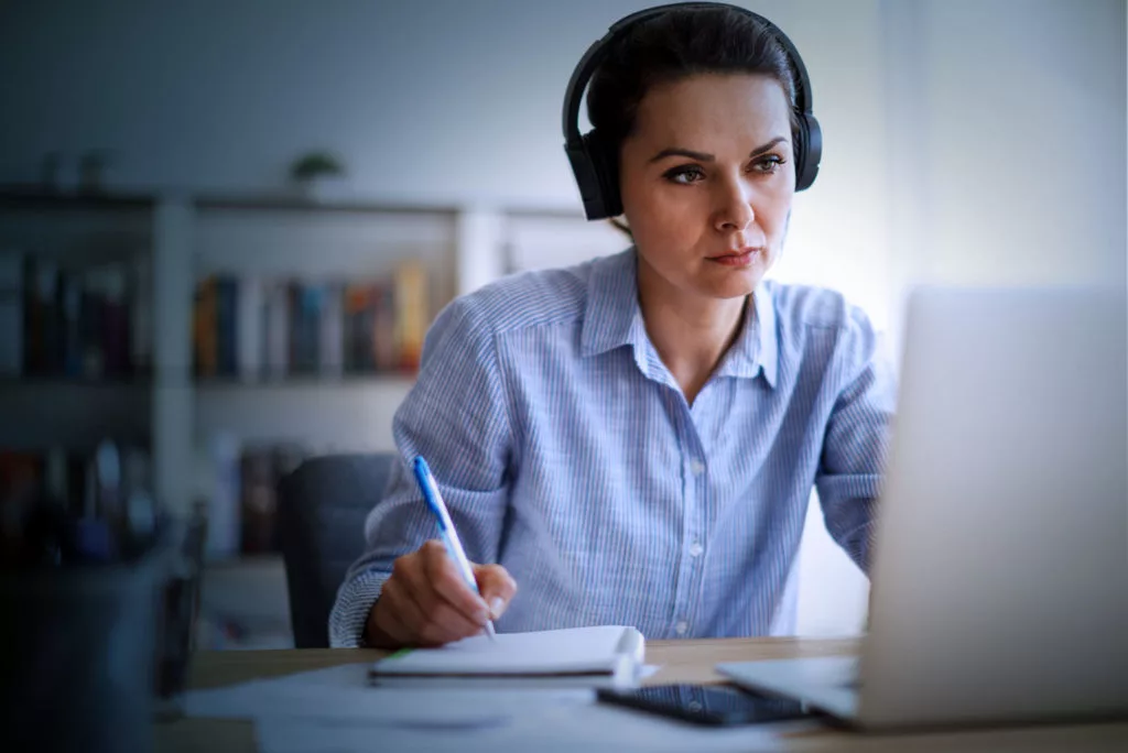 woman looking at laptop with notebook and pen. benefits of microsoft teams
