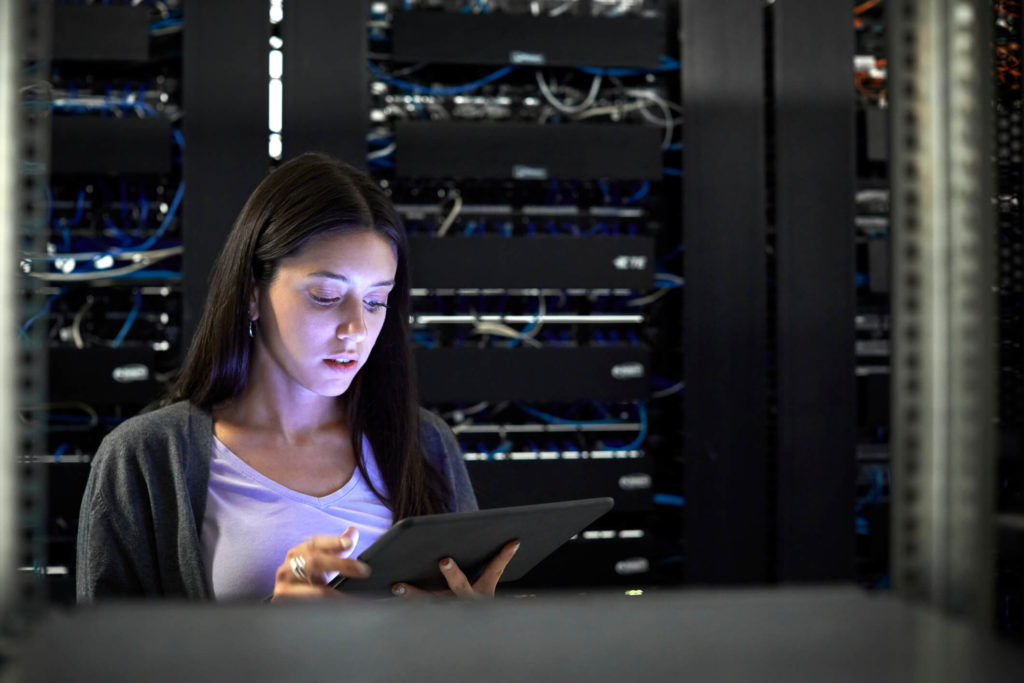Woman looking at tablet in server room configuring cloud security controls